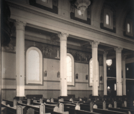 Le récit de la vie de Sainte Philomène peinte au-dessu des vitraux de la nef. Dans cette photo, on entrevoit un petit chemin de la croix qui fut remplacé par celui qui est là maintenant.
A depiction of Saint Philomena's life displayed above the nave windows. This smaller reproduction of the Way of the Cross was later replaced by the present one.