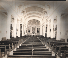 Vu de l'ensemble des nouveaux bancs à l'intérieur ainsi que des tableaux du sanctuaire tel que complété et aussi du gros crucifix qui était situé à la douzième station du chemin de la croix.
View of Monsignor Maillard's paintings in the sanctuary and of the new church pews. The life size crucifix was temporarily used to represent the 12th station of the Way of the Cross.