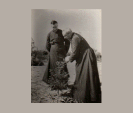 Le curé Charles Maillard avec le Père Albert Gravel qui s`approche d'un sapin dans la cours du presbytère.
Father Charles Maillard with Father Albert Gravel, tending to his evergreens in the presbytery yard.