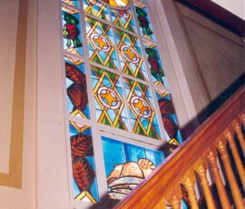 Dans l’escalier qui monte au balcon Ouest, il y a un vitrail qui représente le prophète Isaïe et le sacrifice de l’agneau.
On the West stairway leading to the balcony is Isaiah the Prophet and the Sacrifice of the lamb.
