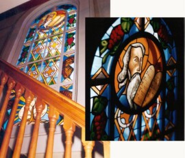 Dans l’escalier qui monte au balcon Est, il y a une représentation de Moïse avec les dix commandements et le buisson ardent.
On the East stairway leading up to the balcony is a stained glass window depicting Moses, holding the Ten Commandements, and the burning bush.